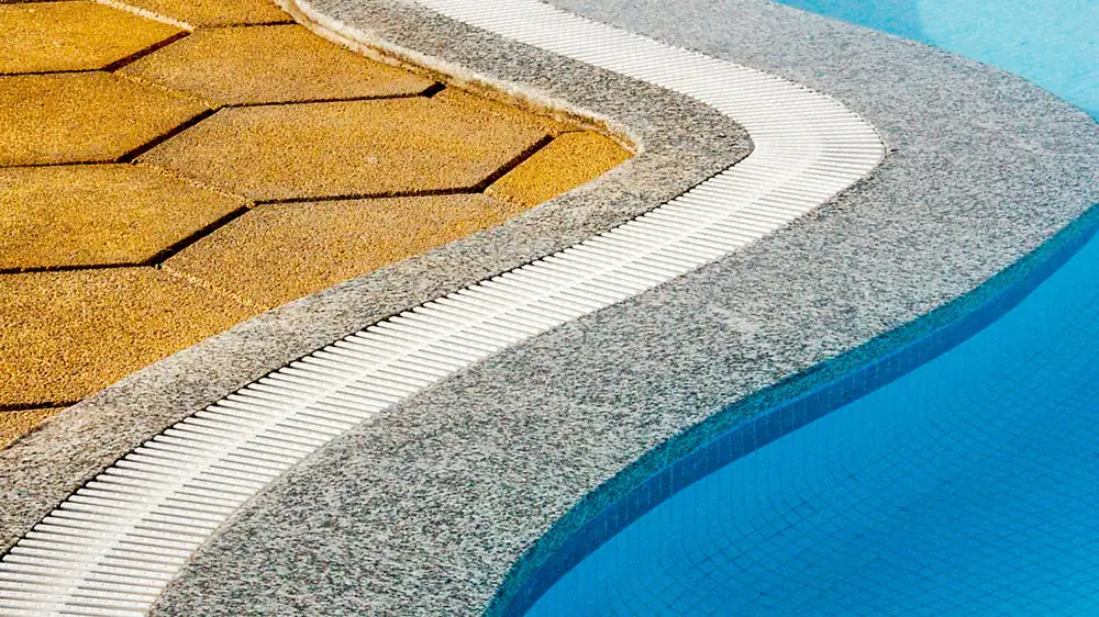 Tile and stone coping wrapping the curved edge of a pool