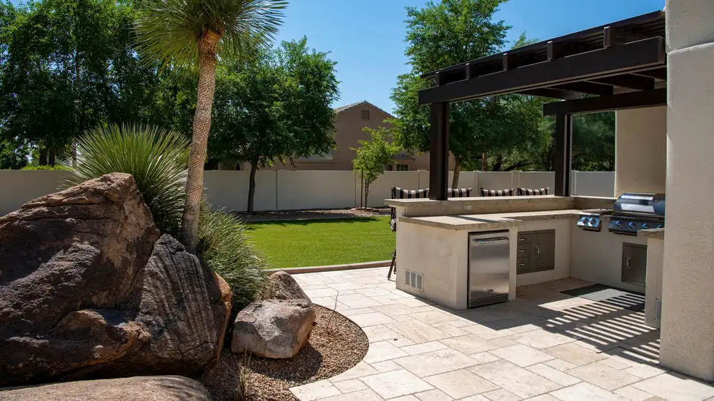 Outdoor kitchen on a sunny patio with landscaping