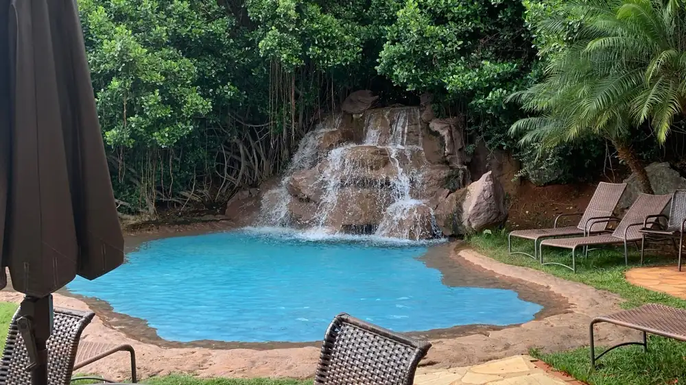 A free form pool with a boulder waterfall set into heavy planting