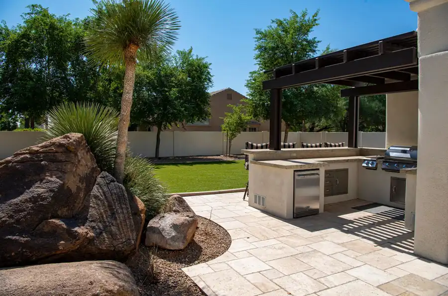 Outdoor kitchen on a sunny patio with landscaping
