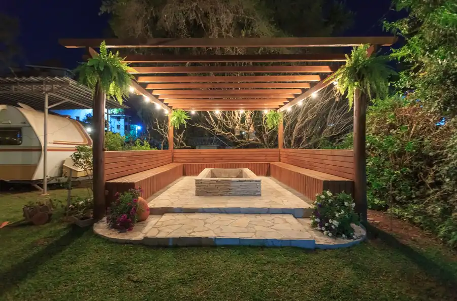 An illuminated gazebo with a fireplace and benches at night