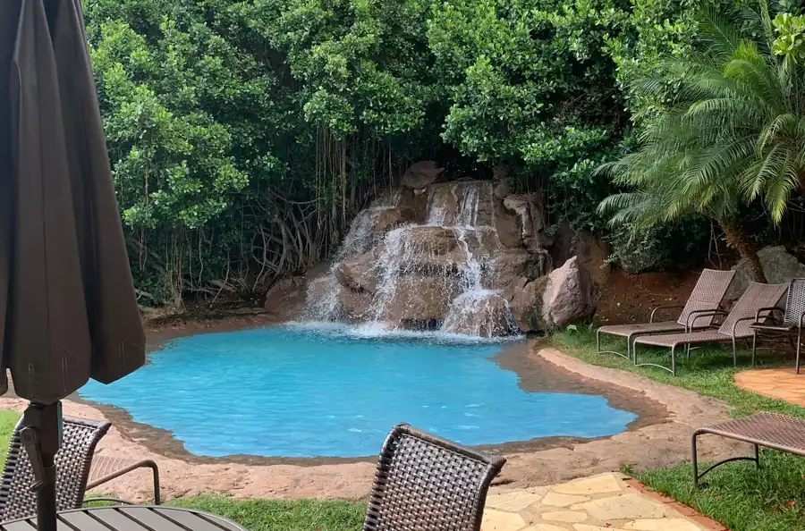 A free form pool with a boulder waterfall set into heavy planting