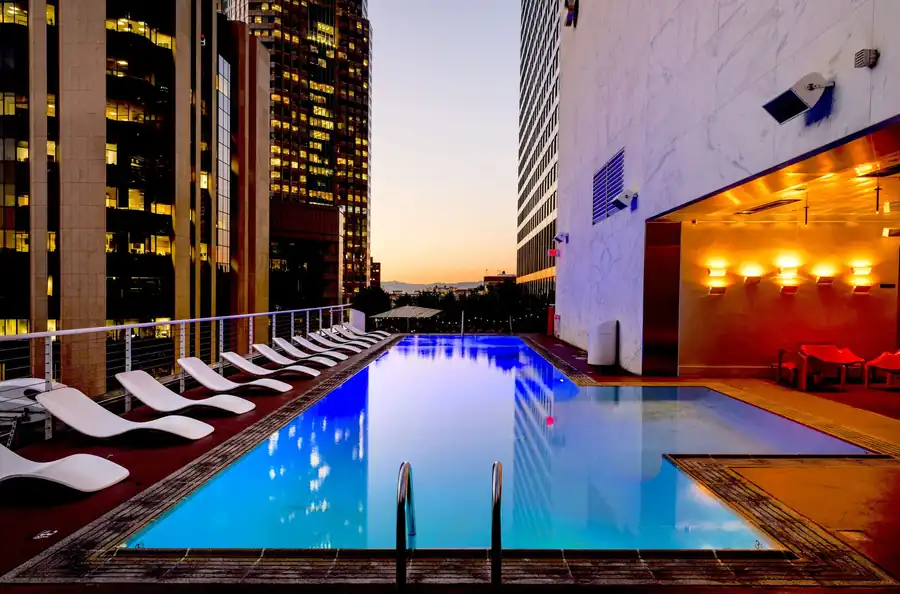 A lap pool lit blue at night between two buildings