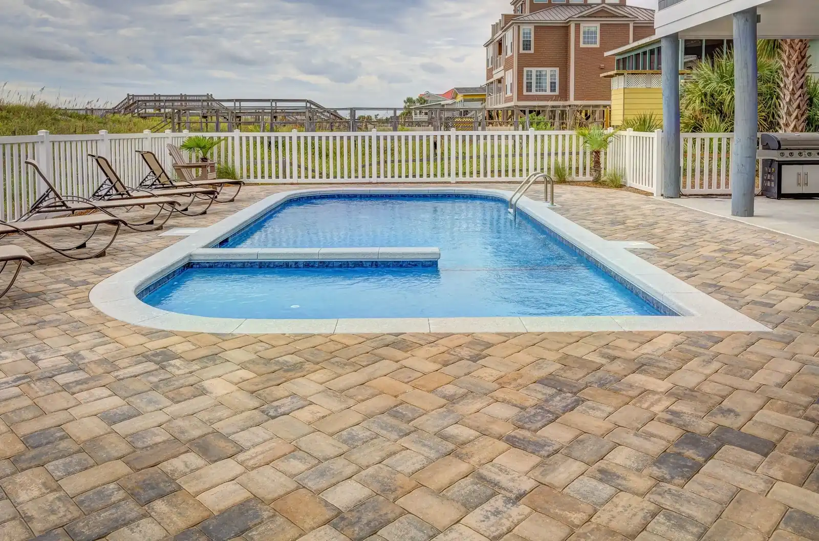 A residential pool with paver decking and lounge chairs