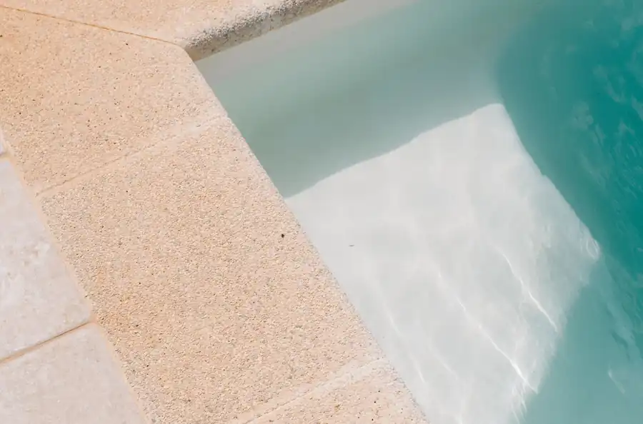 Close view of a pool edge with turquoise water in sunlight