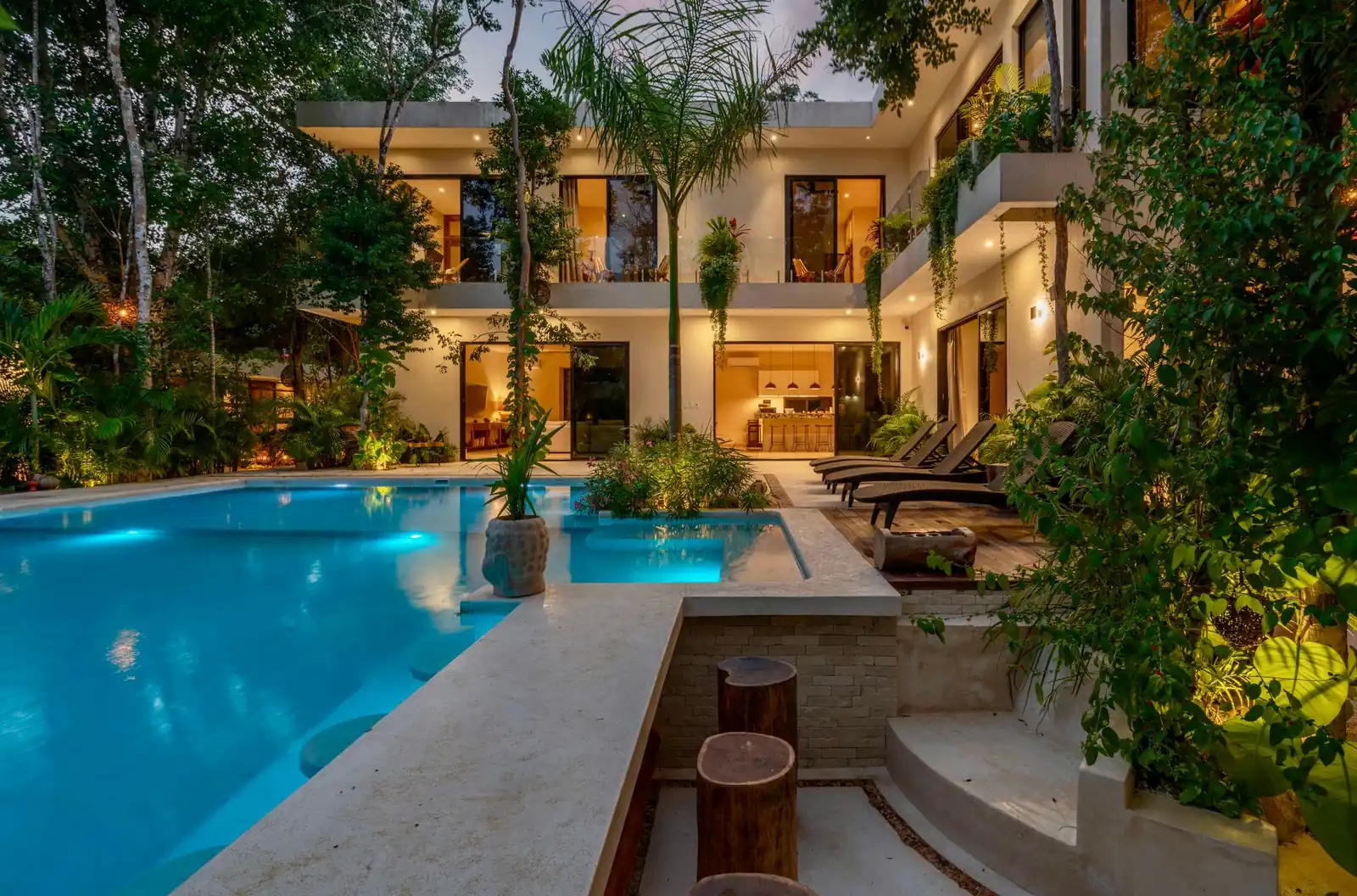 A custom gunite pool lit at dusk beside a Texas home with a covered patio