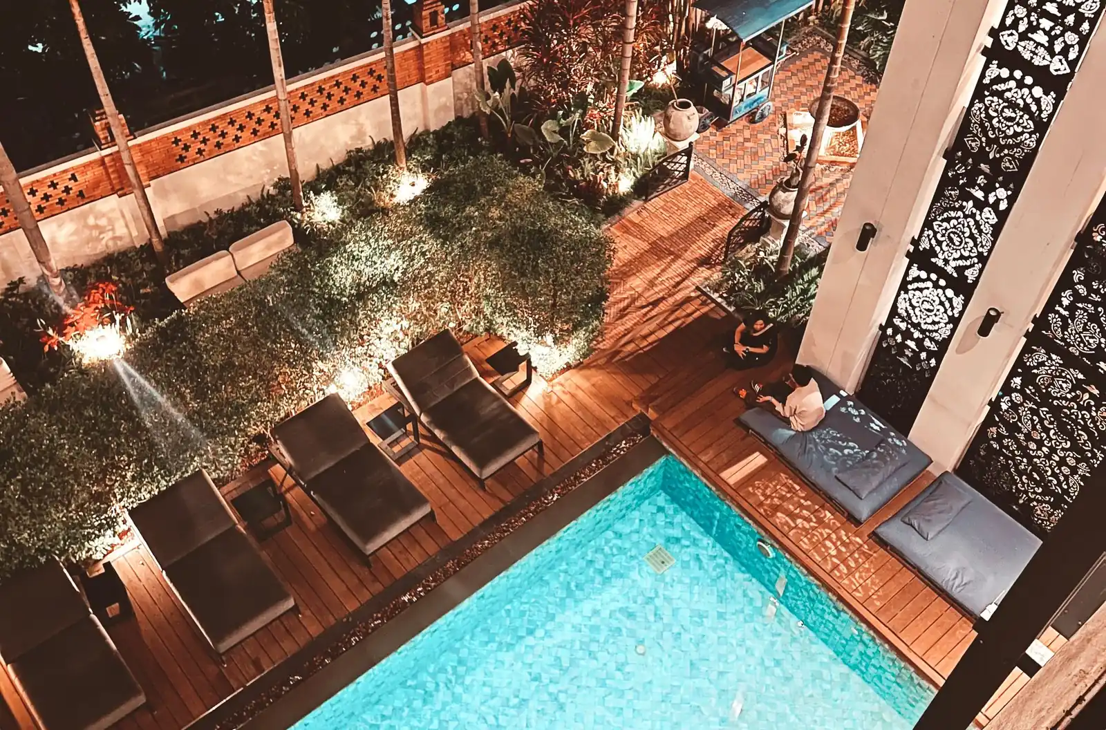 A backyard pool lit from within at night, seen from above