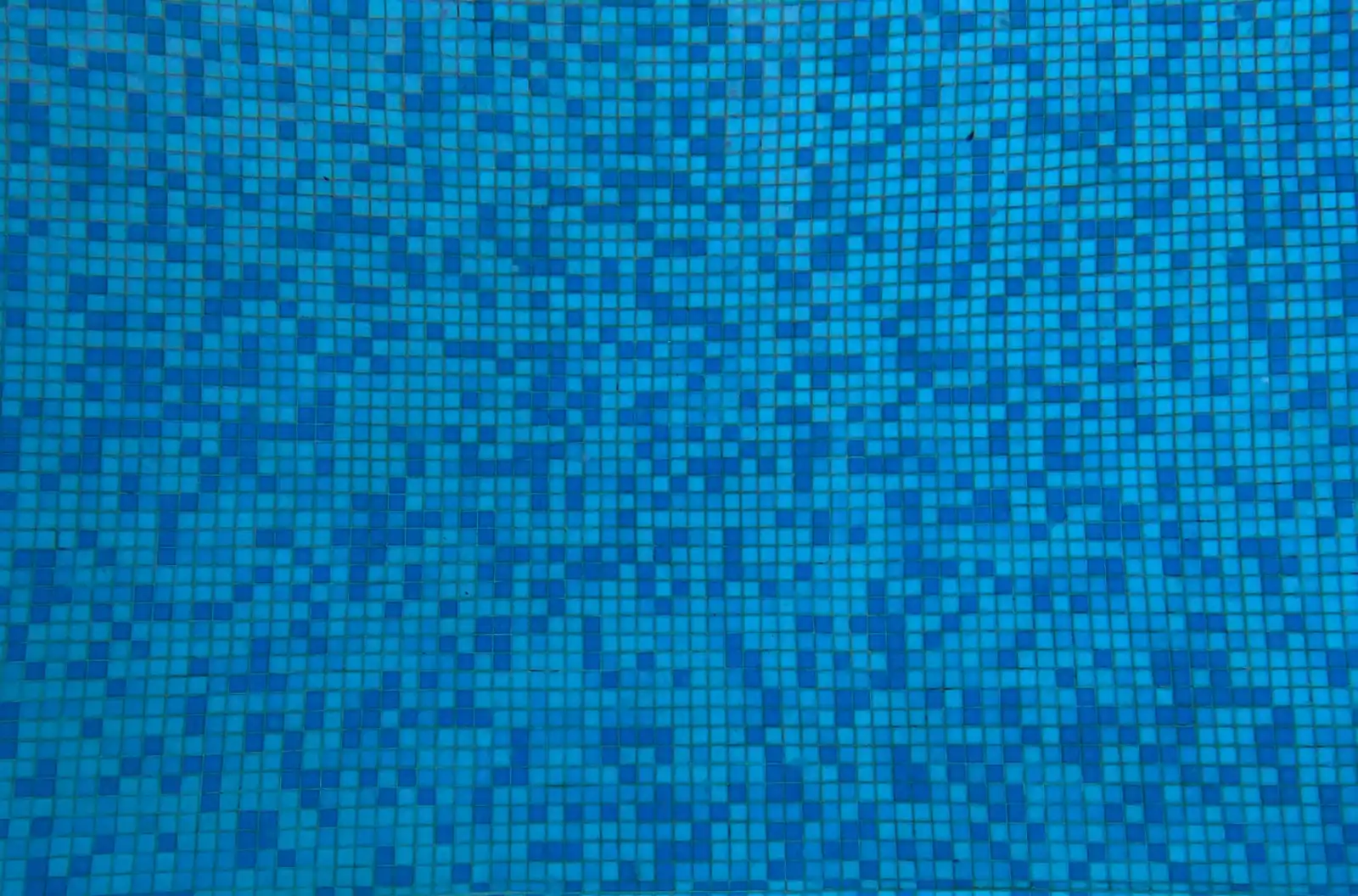 Close detail of blue mosaic tile and a drain inside a pool