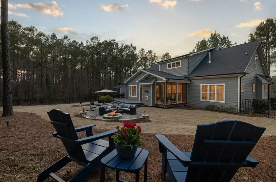 Backyard fire pit with seating at sunset behind a house