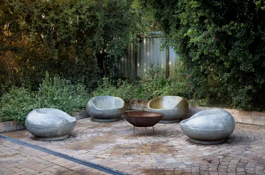 Stone patio seating around a fire bowl surrounded by greenery