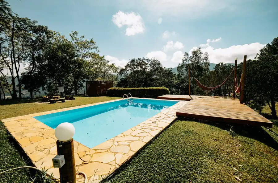 Free form pool with a raised wooden deck and stone coping