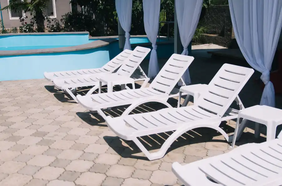White loungers lined along a sunlit pool deck